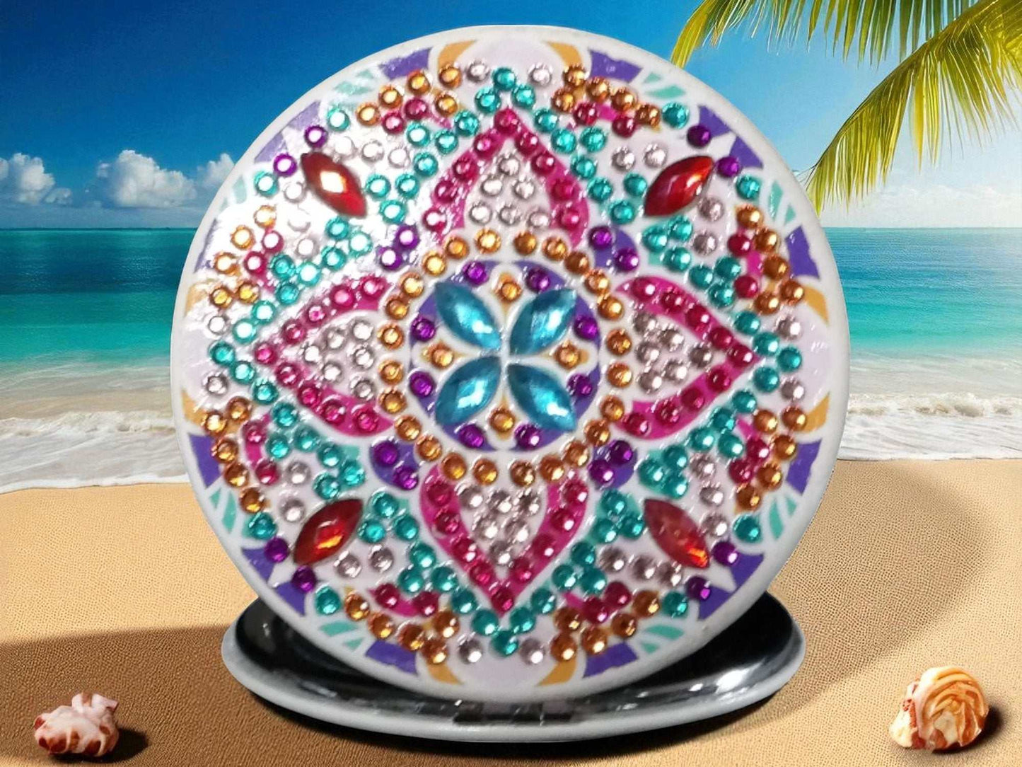 Colorful star round pocket mirror with mandala design and decorative jewels on beach background