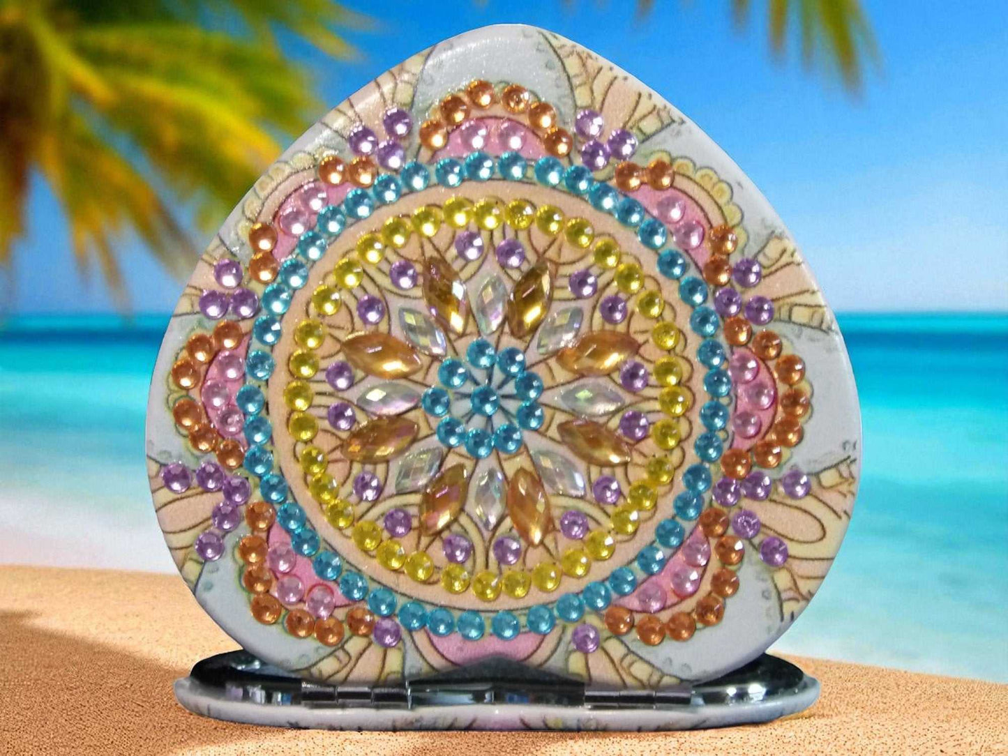 Golden heart shape mandala design pocket mirror with magnification and regular sides on beach background