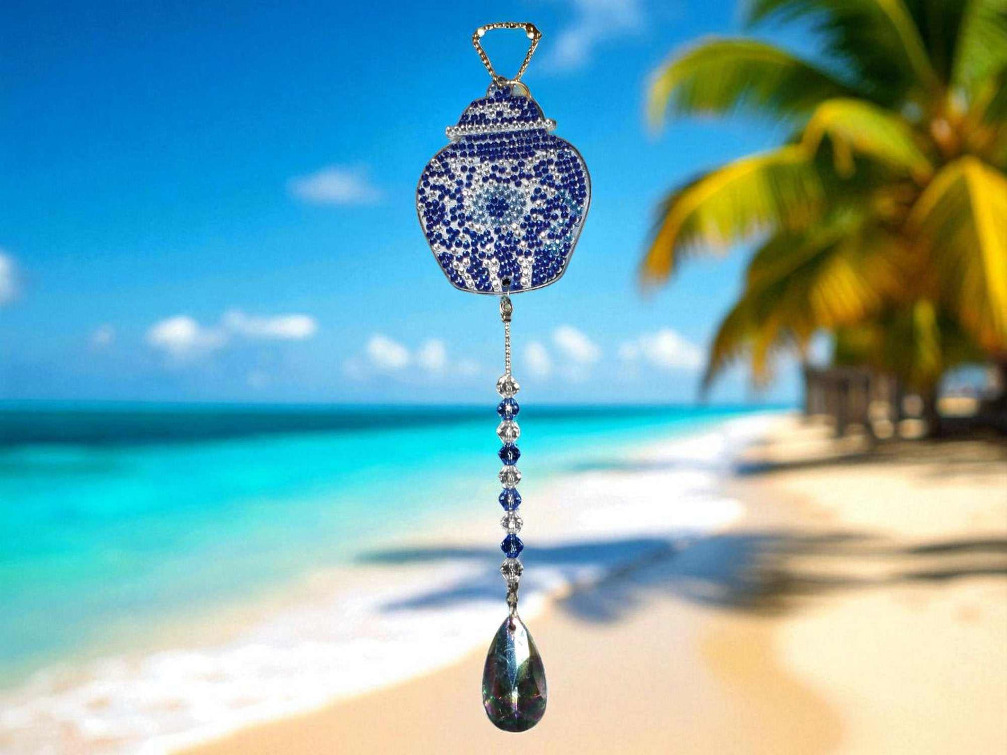 Blue antique style handcrafted sun and wind catcher hanging outdoors by beach with palm trees