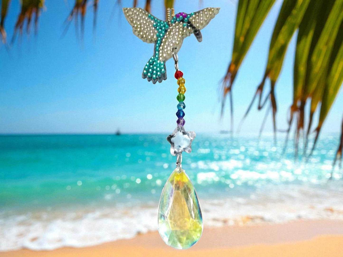 Blue and white hummingbird sun catcher with crystal prism hanging by the beach