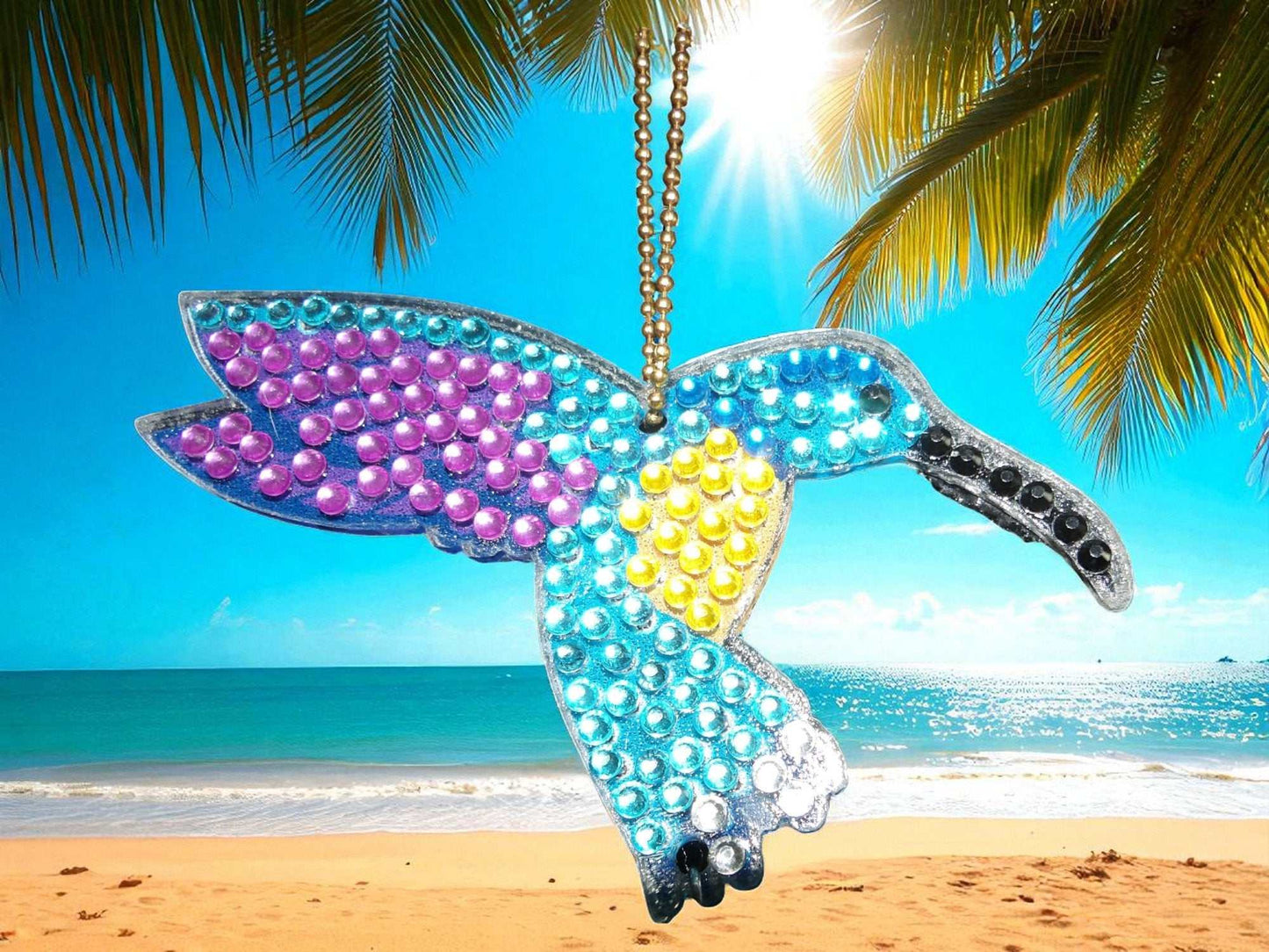 Purple Wing Hummingbird sun catcher hanging with ocean and palm trees background