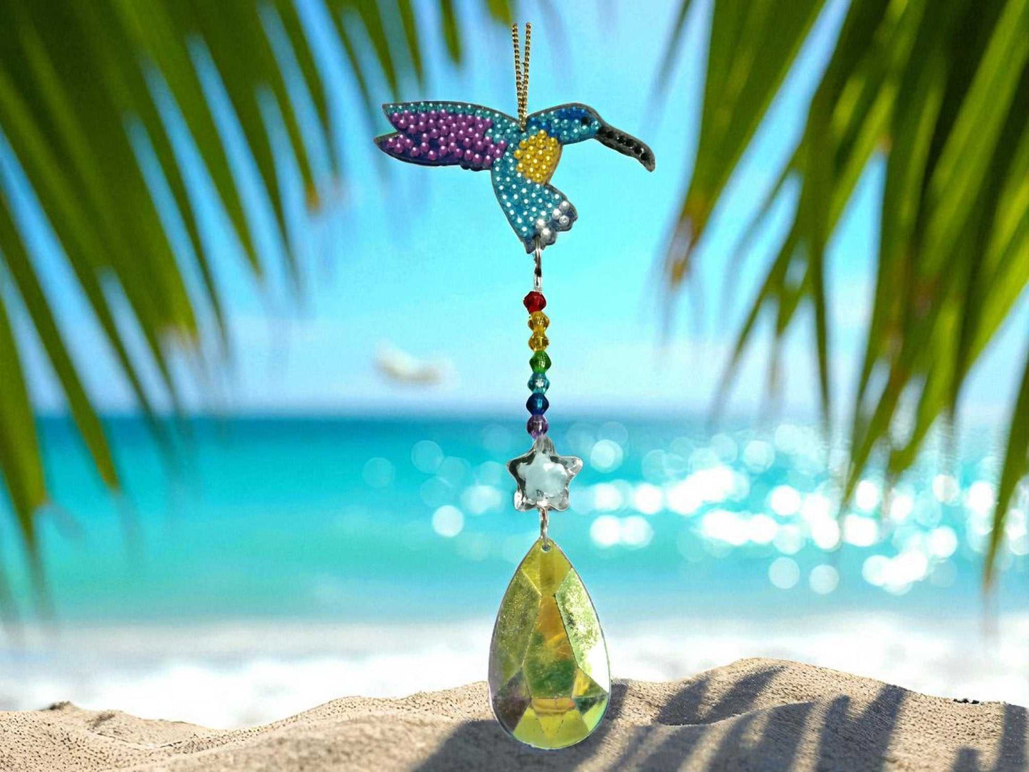Purple Wing Hummingbird sun catcher hanging with crystal and beads by beach background