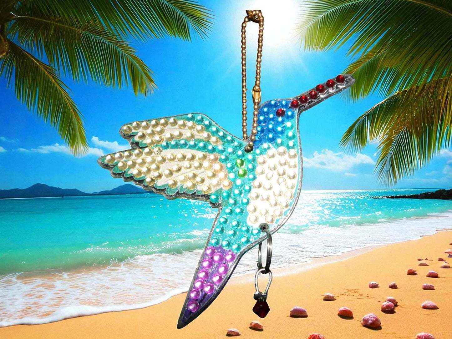 Blue white purple hummingbird sun wind catcher hanging on tropical beach background