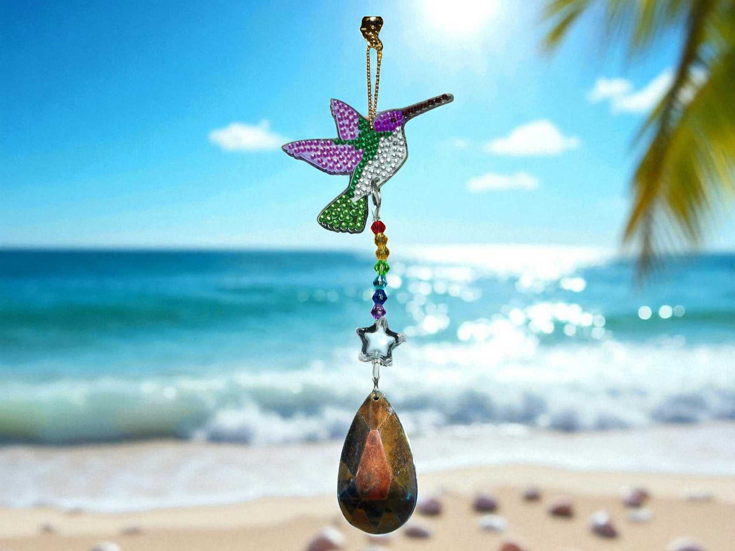 Handcrafted green and purple wings hummingbird sun catcher with hanging crystal beads by the beach
