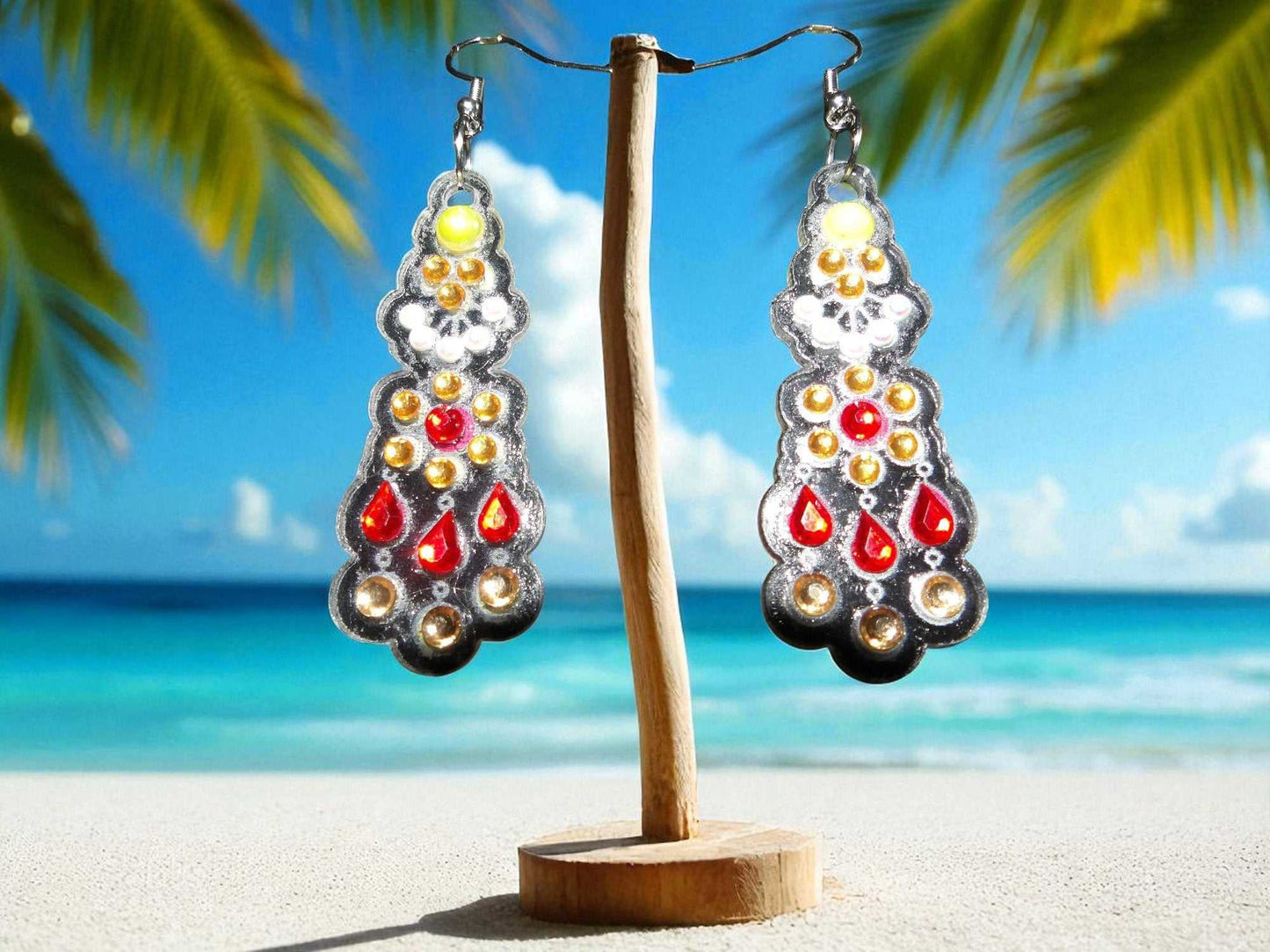 Yellow and white pearl gold and red handmade earrings on wooden stand at beach background