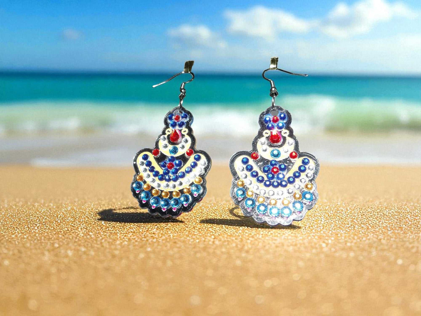 handmade blue and yellow earrings with bead accents on sandy beach background