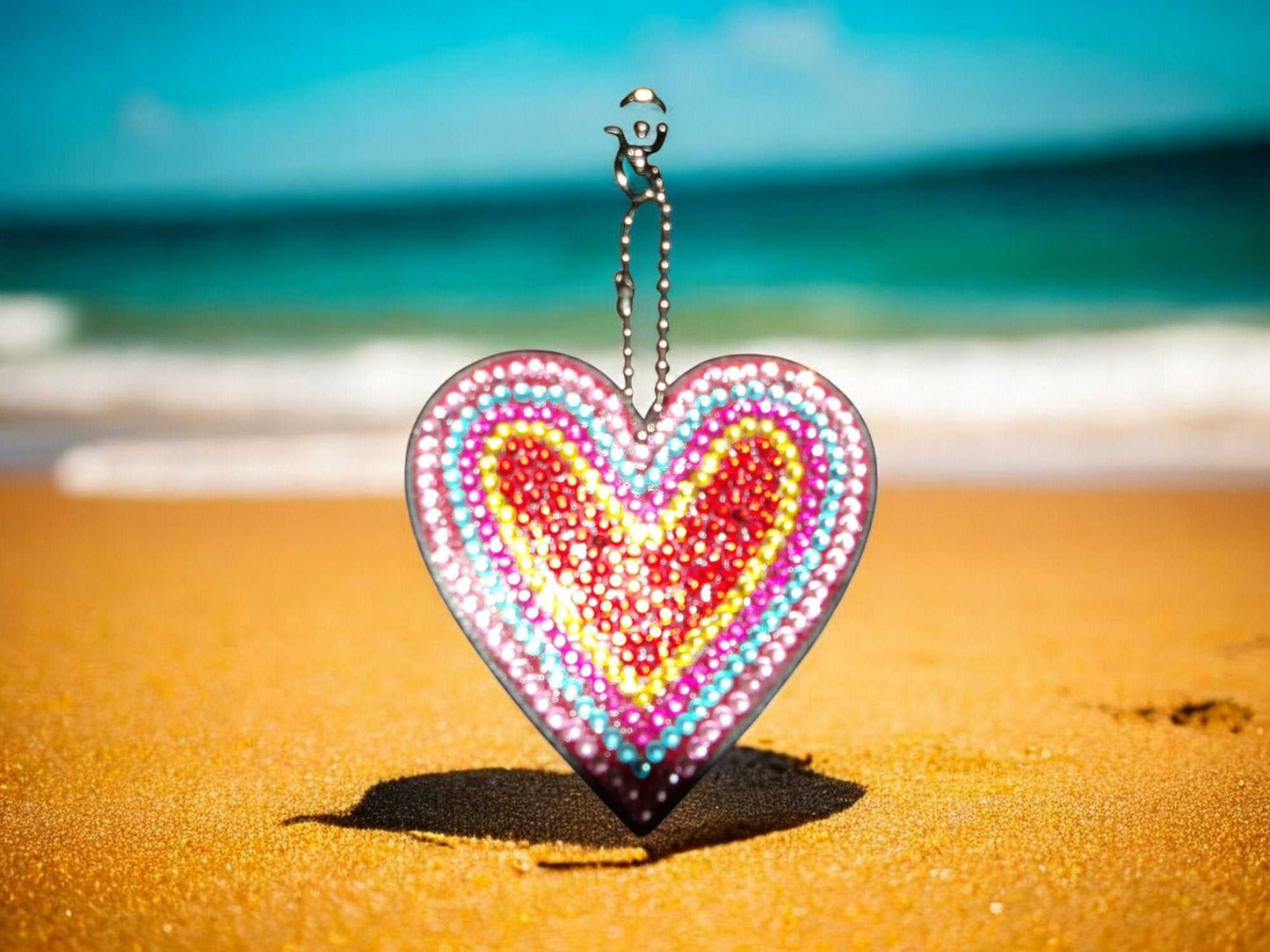 Red Center Heart Keychain with colorful beaded design on sandy beach background