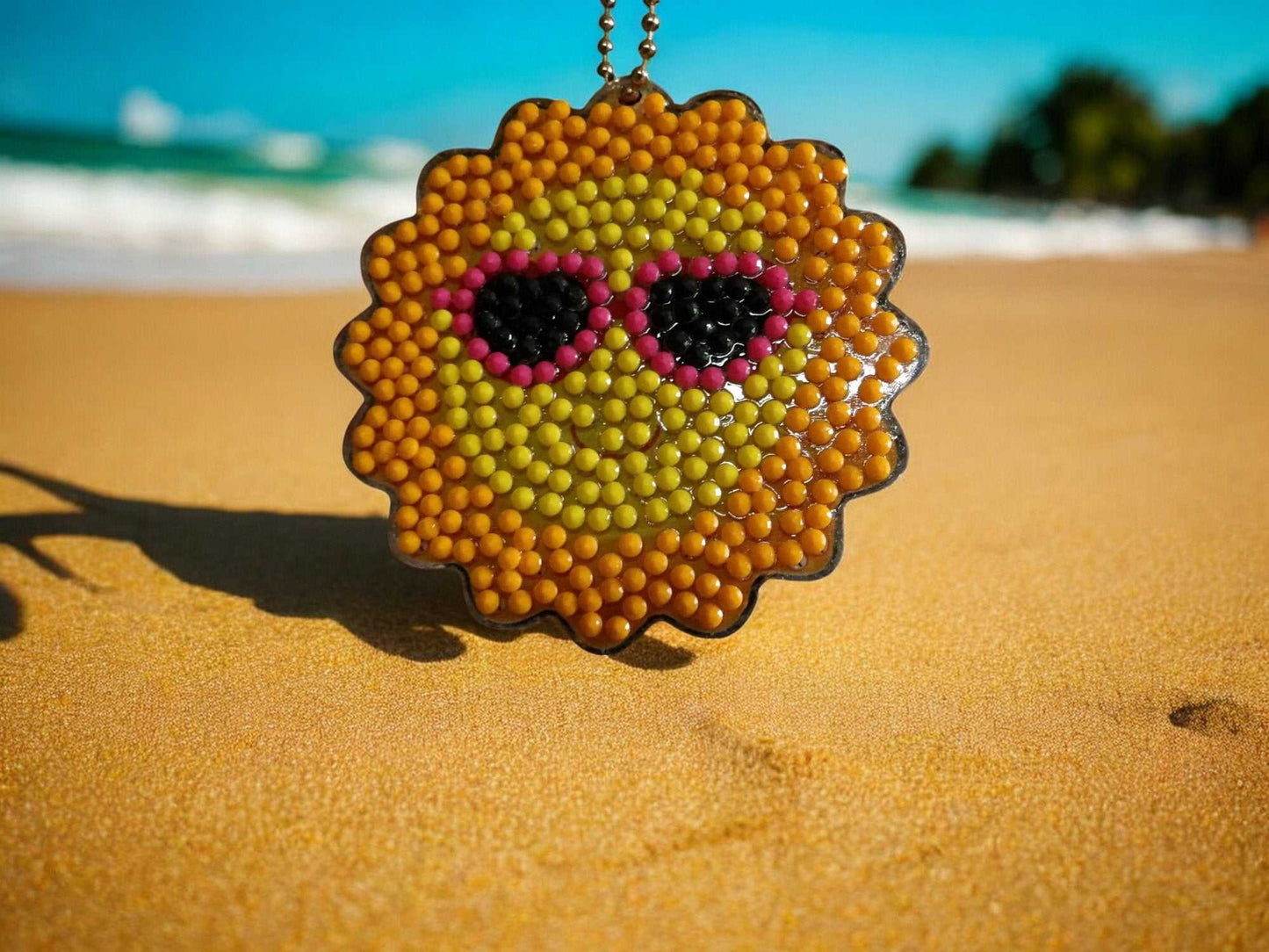 Keychain Sun with sunglasses keychain on sandy beach background