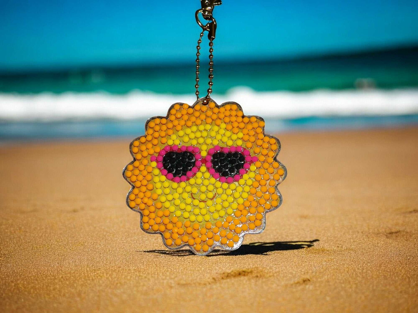 Keychain Sun w/Sunglasses Keychain hanging on sandy beach with ocean background