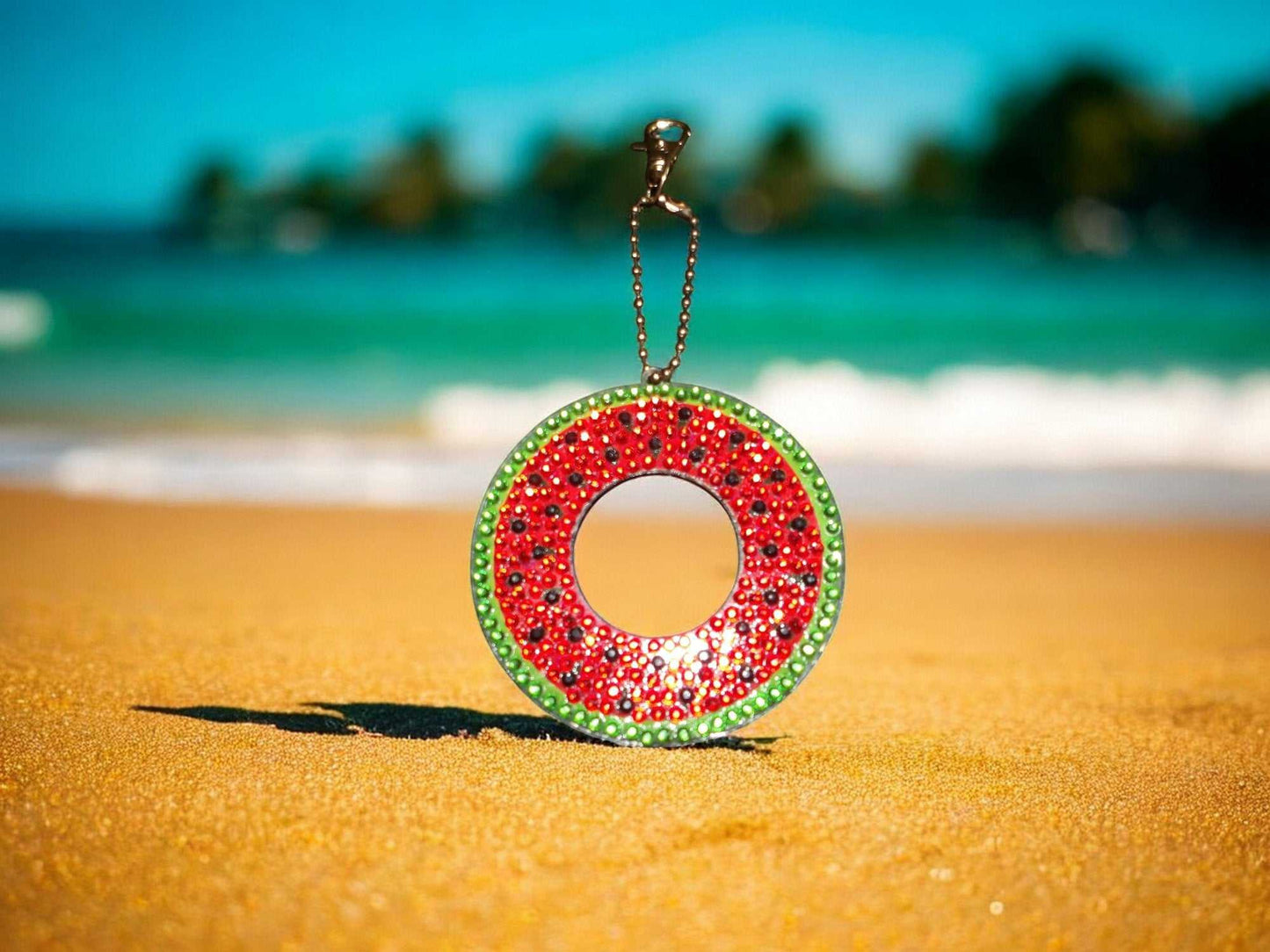 Colorful watermelon keychain with rhinestones on sandy beach background