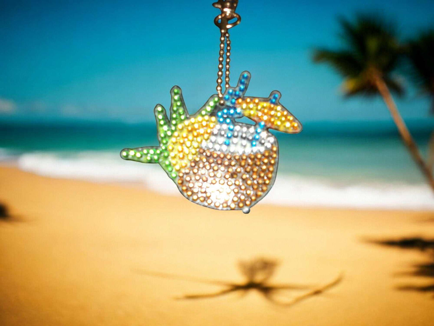 Summer Drink w/Umbrella keychain with colorful beads hanging against a beach background