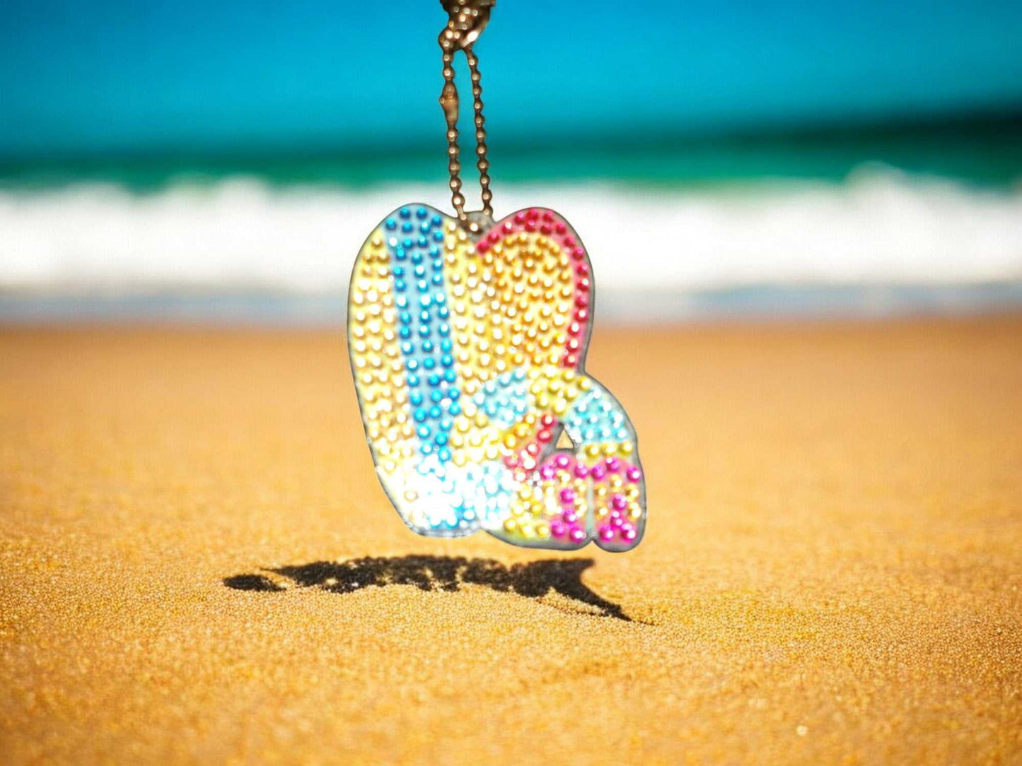 Surfs Up Surf Boads Keychain colorful hanging on sandy beach background