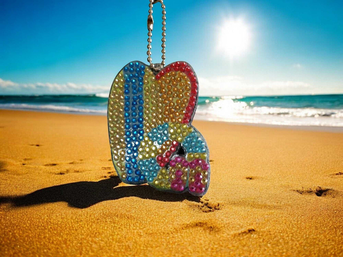 Surfs Up Surf Boads Keychain with colorful beads hanging on a beach with ocean background