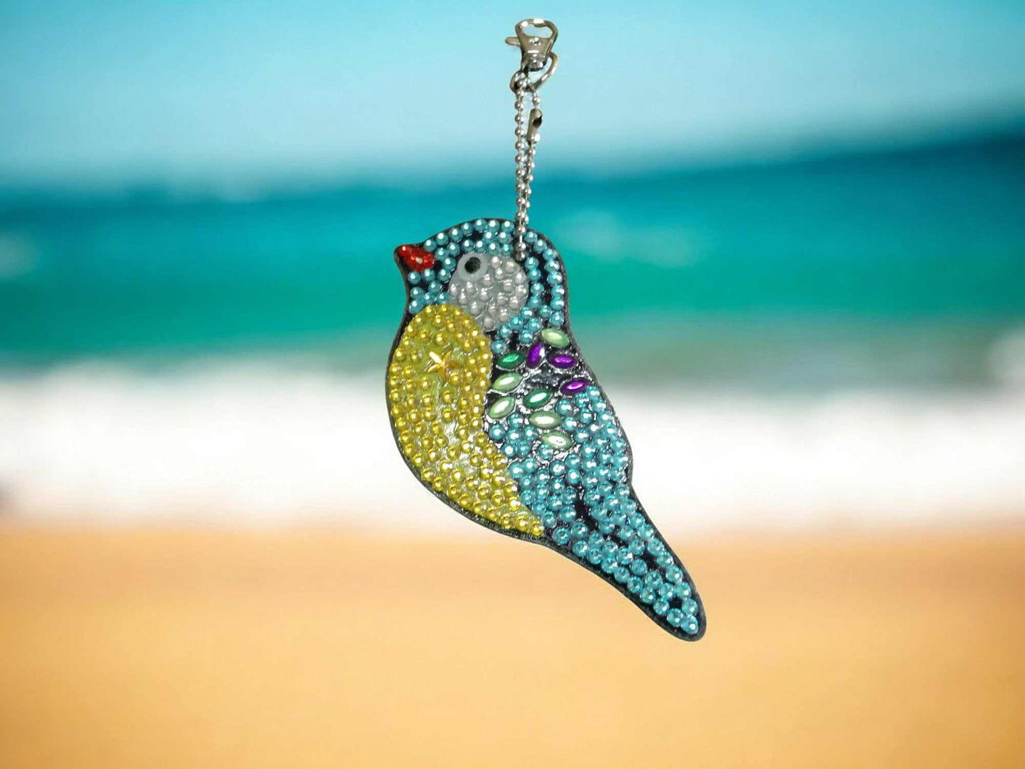 Blue and yellow robin bird keychain with colorful rhinestones hanging outdoors