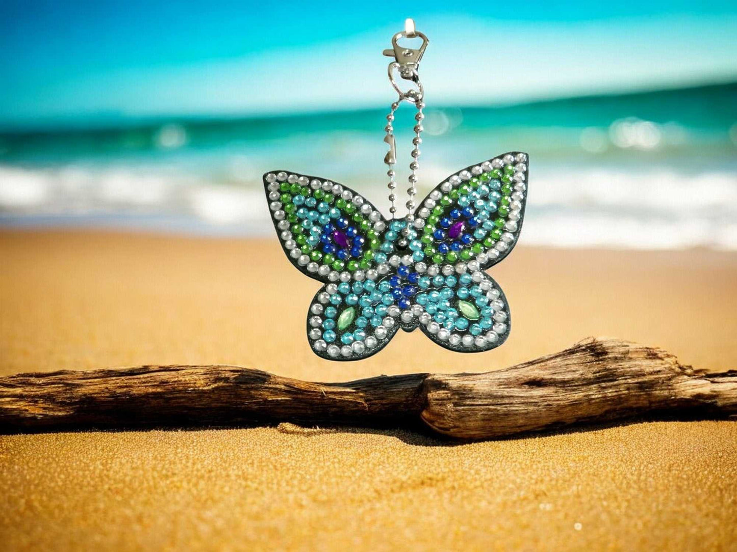 Colorful Blues Butterfly Keychain with beads hanging on chain over beach sand and driftwood
