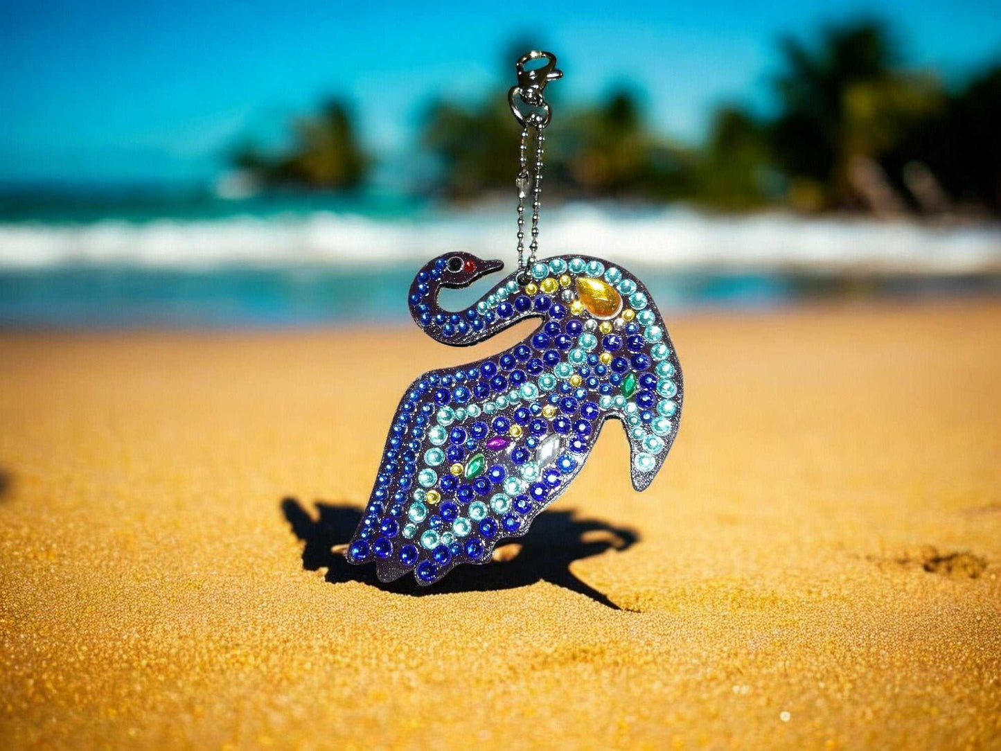 Multi-blue swan keychain with sparkling beads on sandy beach background