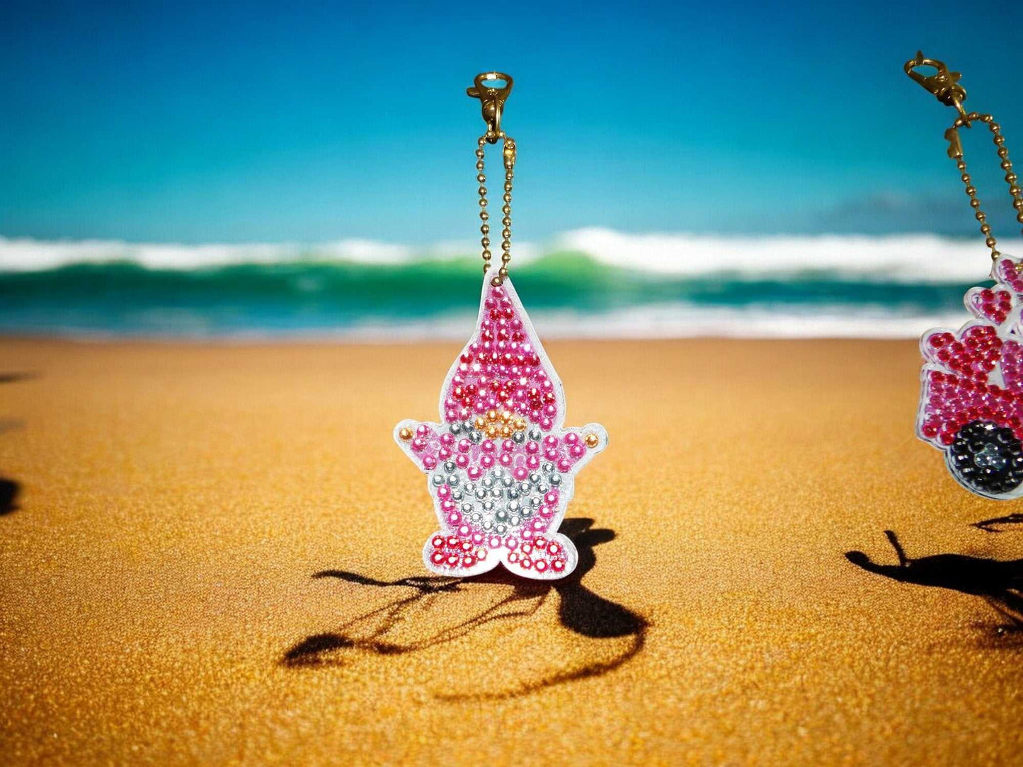 Happy Pink Gnome keychain with beads on sandy beach background