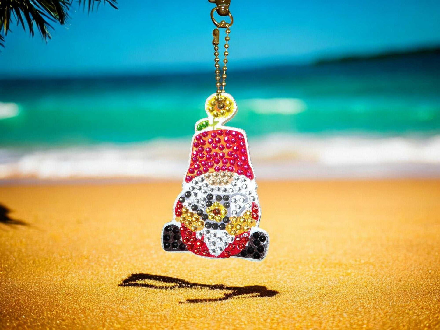 Red Hat Gnome Keychain with colorful beads hanging on gold chain at sunny beach background