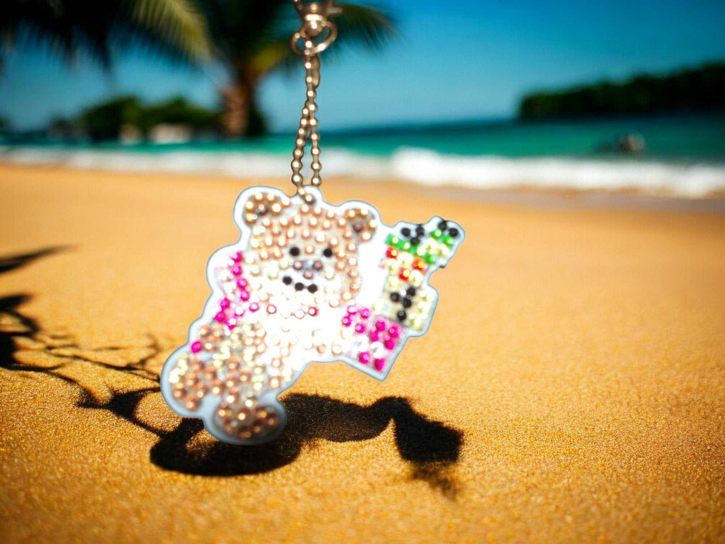 Teddy bear with presents keychain hanging on a sandy beach background