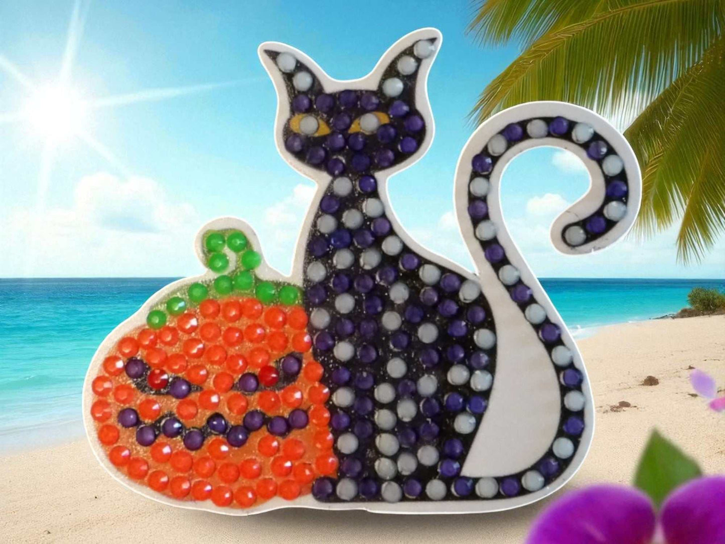 Glow in the dark black cat magnet with orange pumpkin design on beach background