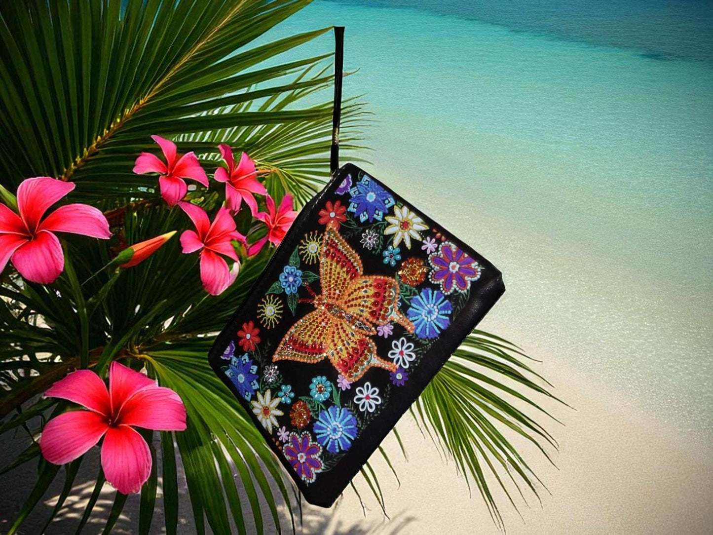 Golden Butterfly Large Hand Clutch with colorful butterfly and floral embroidery hanging on palm leaves by tropical beach background