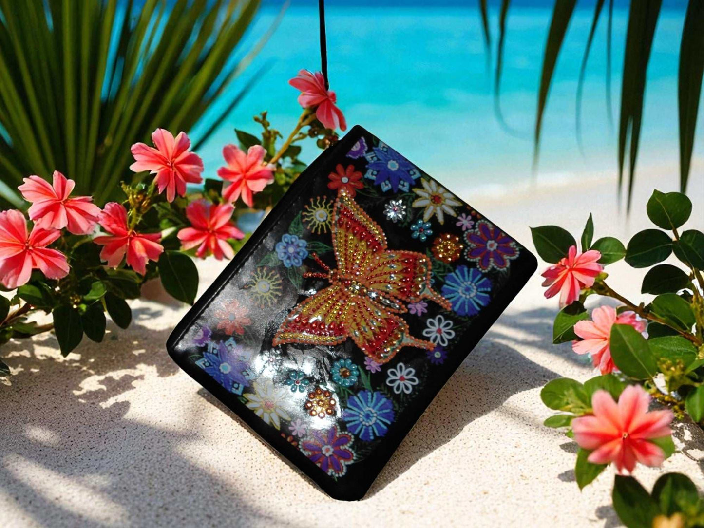 Golden Butterfly Large Hand Clutch with intricate butterfly and floral design on black background by poolside with pink flowers