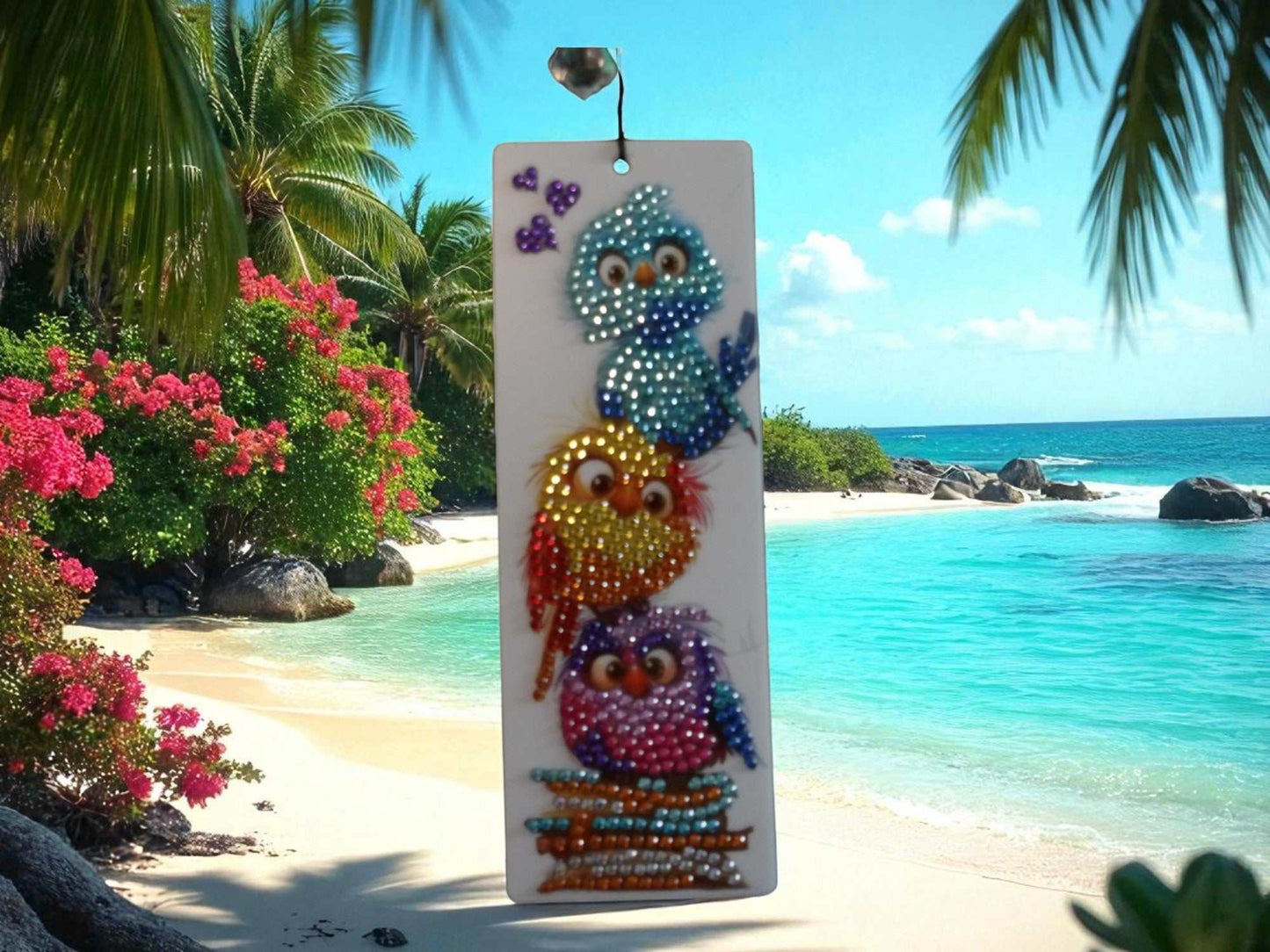 Colorful birds bookmark with vibrant gem-studded bird designs against a tropical beach background