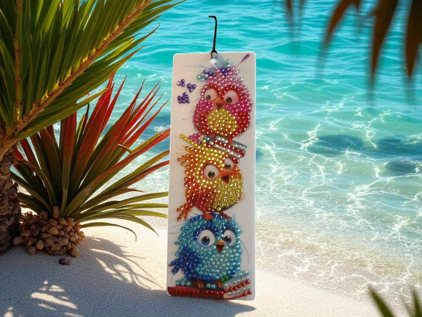 Surprised colorful birds bookmark with vibrant beaded design hanging by tropical beach