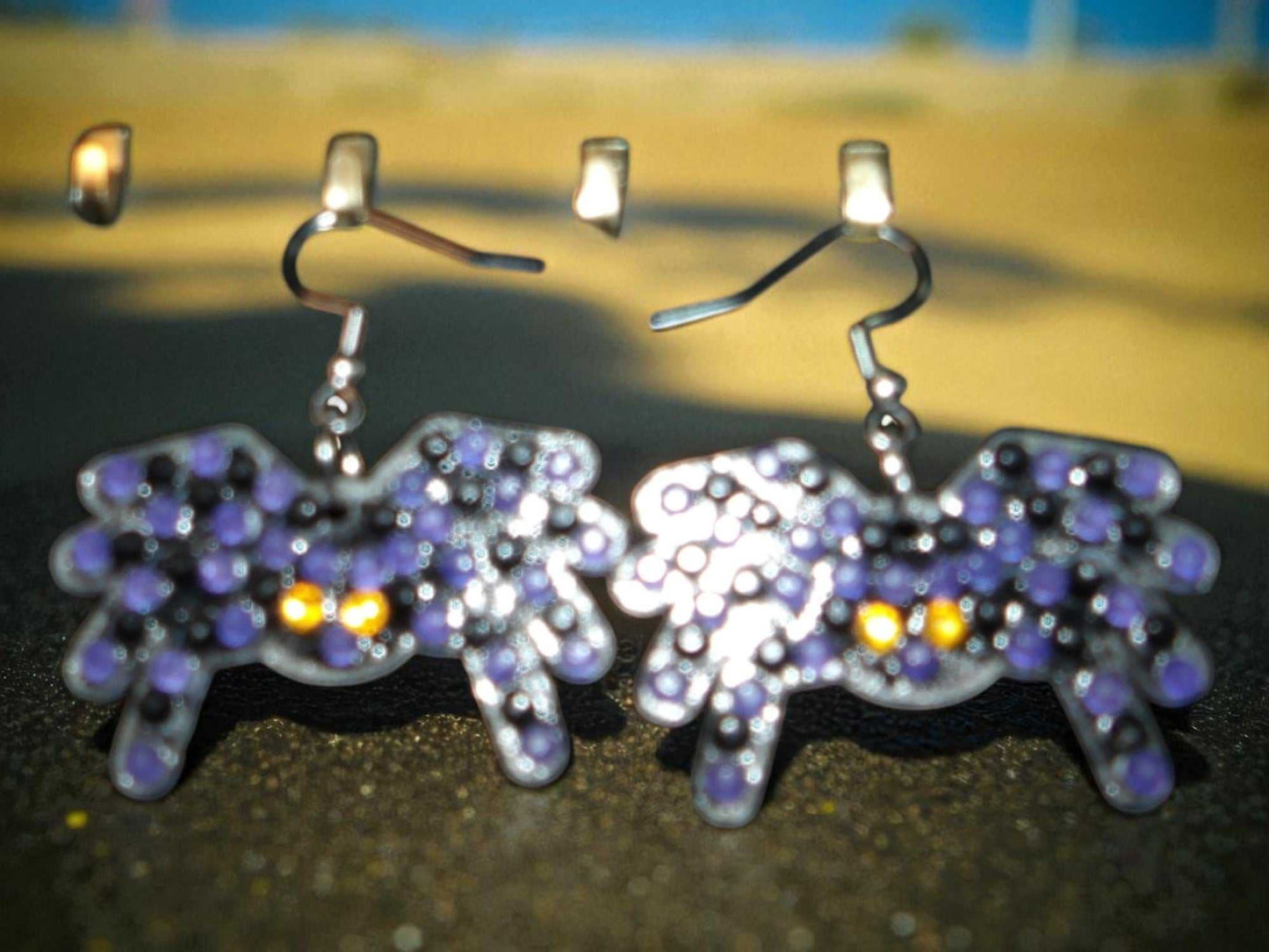 Glow in the dark spider shaped handmade earrings with purple and yellow accents