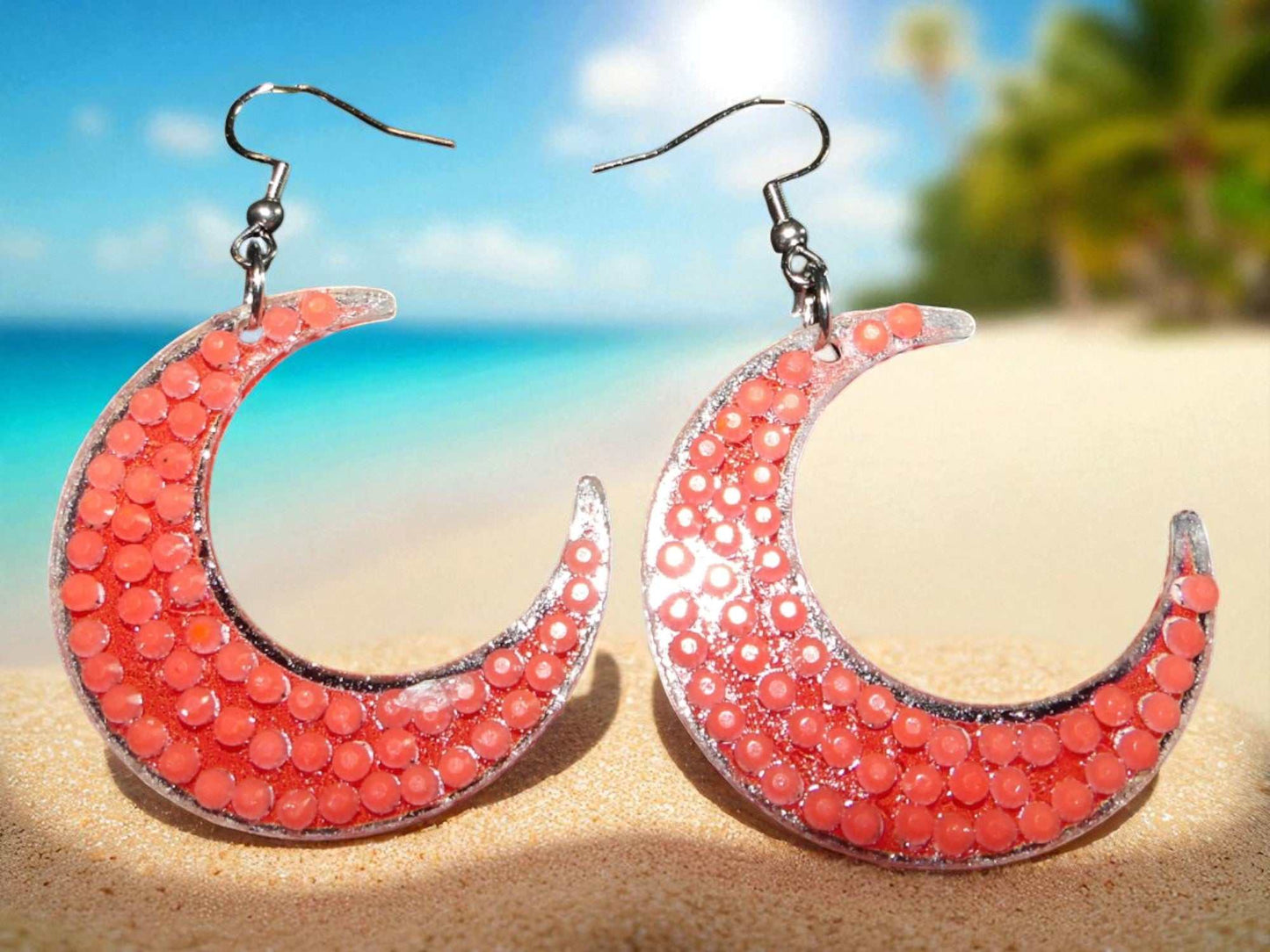 Glow in the dark half moon earrings with coral beads on beach background