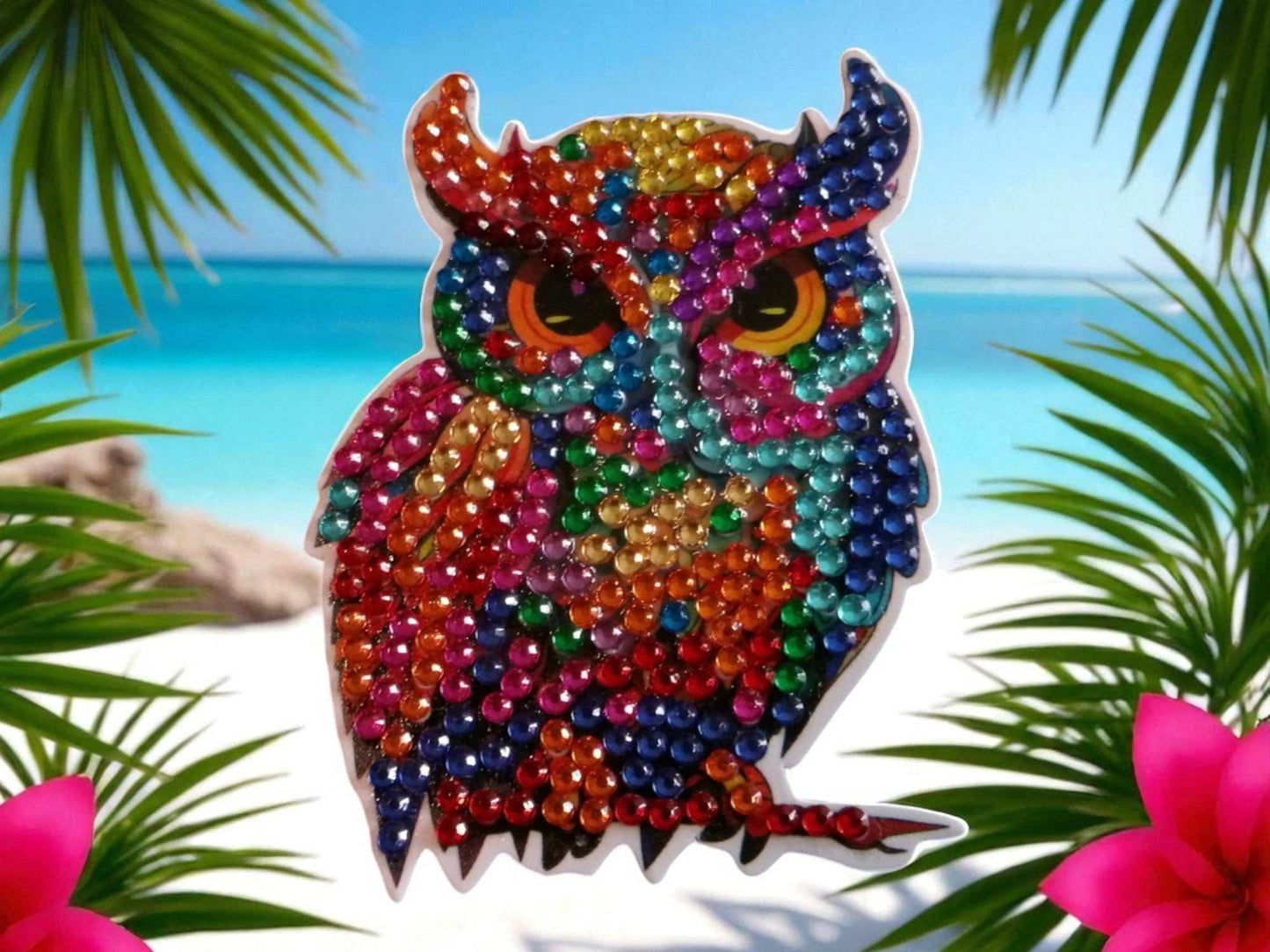Colorful owl magnet decorated with vibrant beads against a beach background