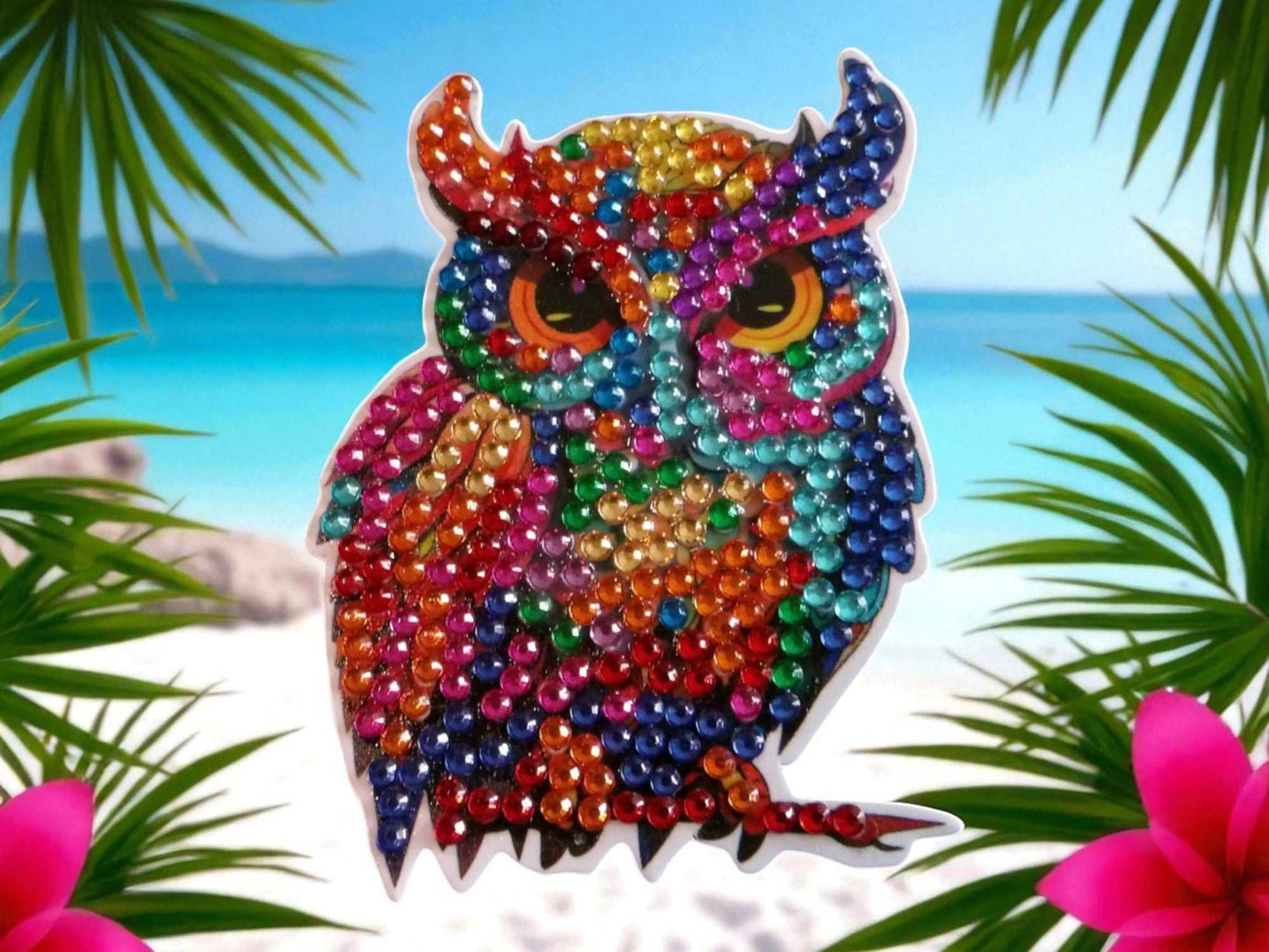 vibrant colorful owl magnet with multicolored gems on tropical beach background