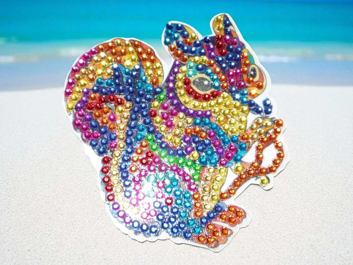 Colorful squirrel magnet decorated with vibrant, multicolored rhinestones on a white background