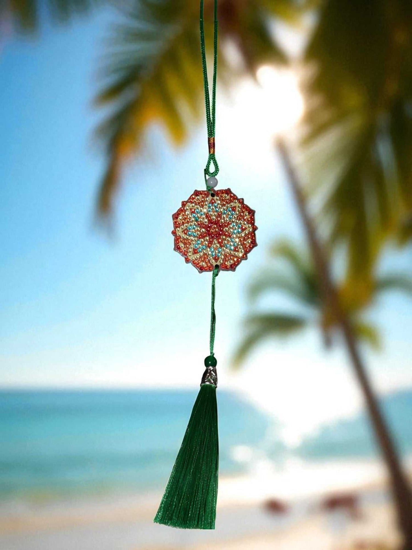 Green red design car ornament with tassel hanging by the beach background