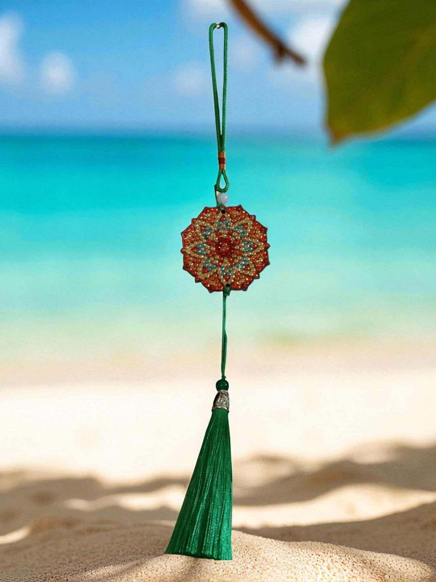 Green red design car ornament with tassel hanging in beach background