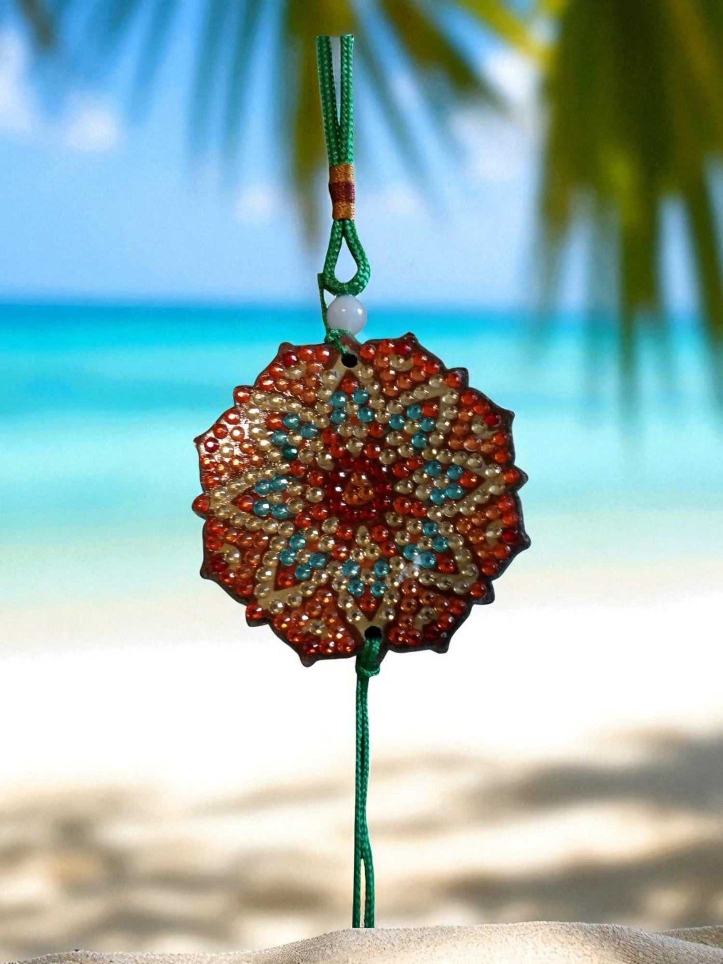 Green Red Design car ornament hanging with intricate colorful pattern and green string background beach