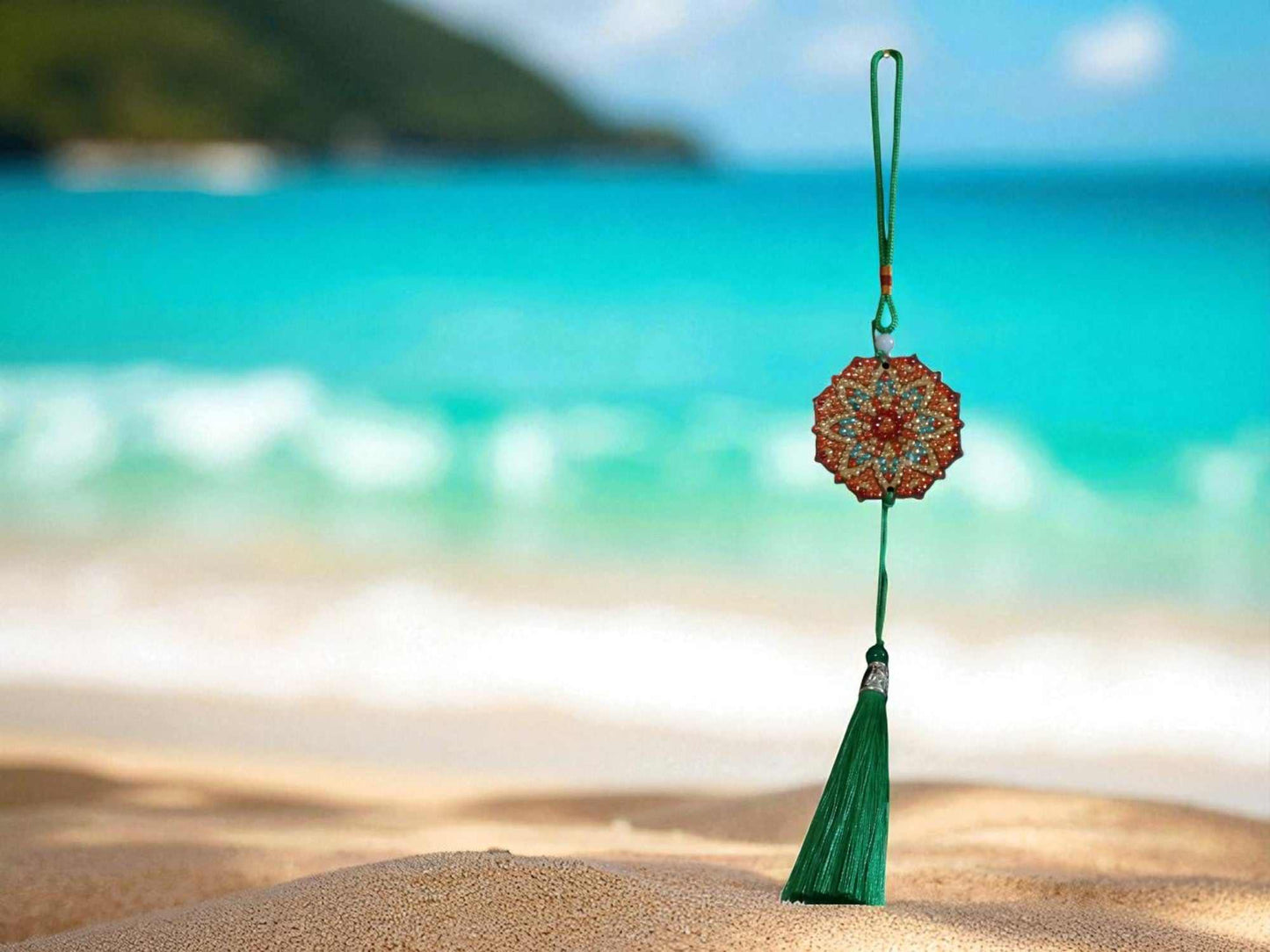 Green red design decorative car ornament with tassel hanging by beach background