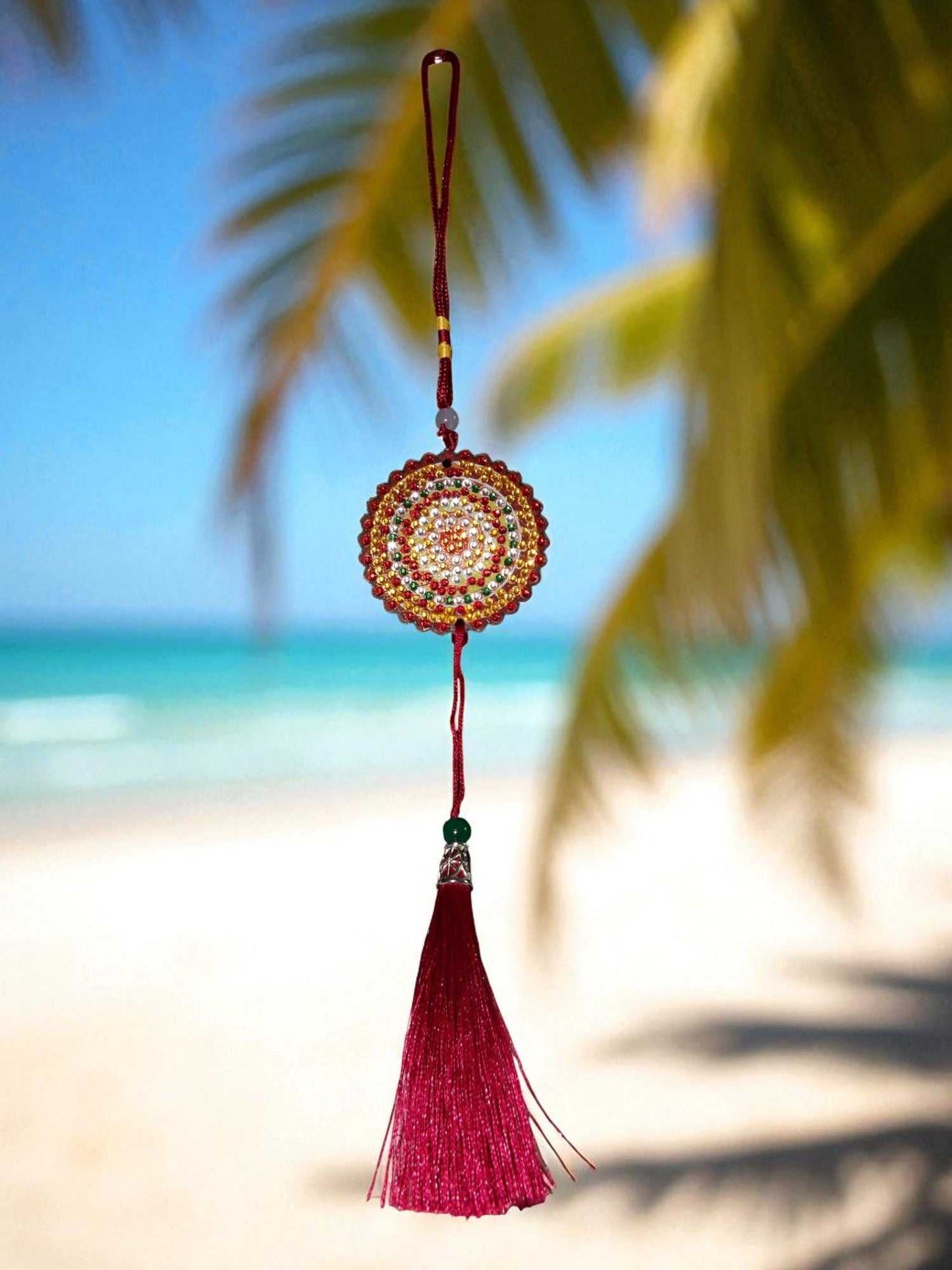 Deep red colorful design car ornament hanging with tassel against beach background