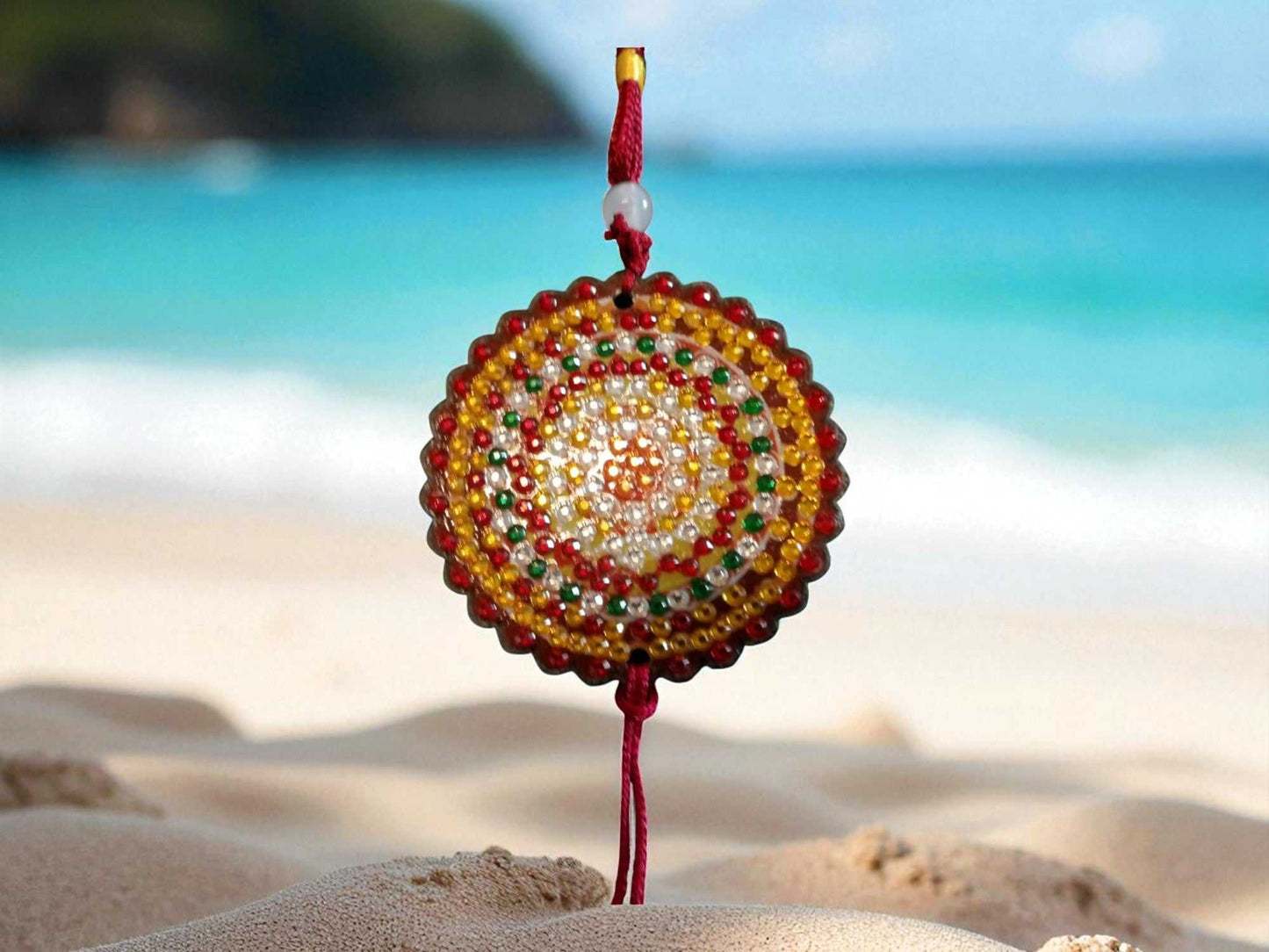 Deep red colorful design car ornament with beads hanging on beach background