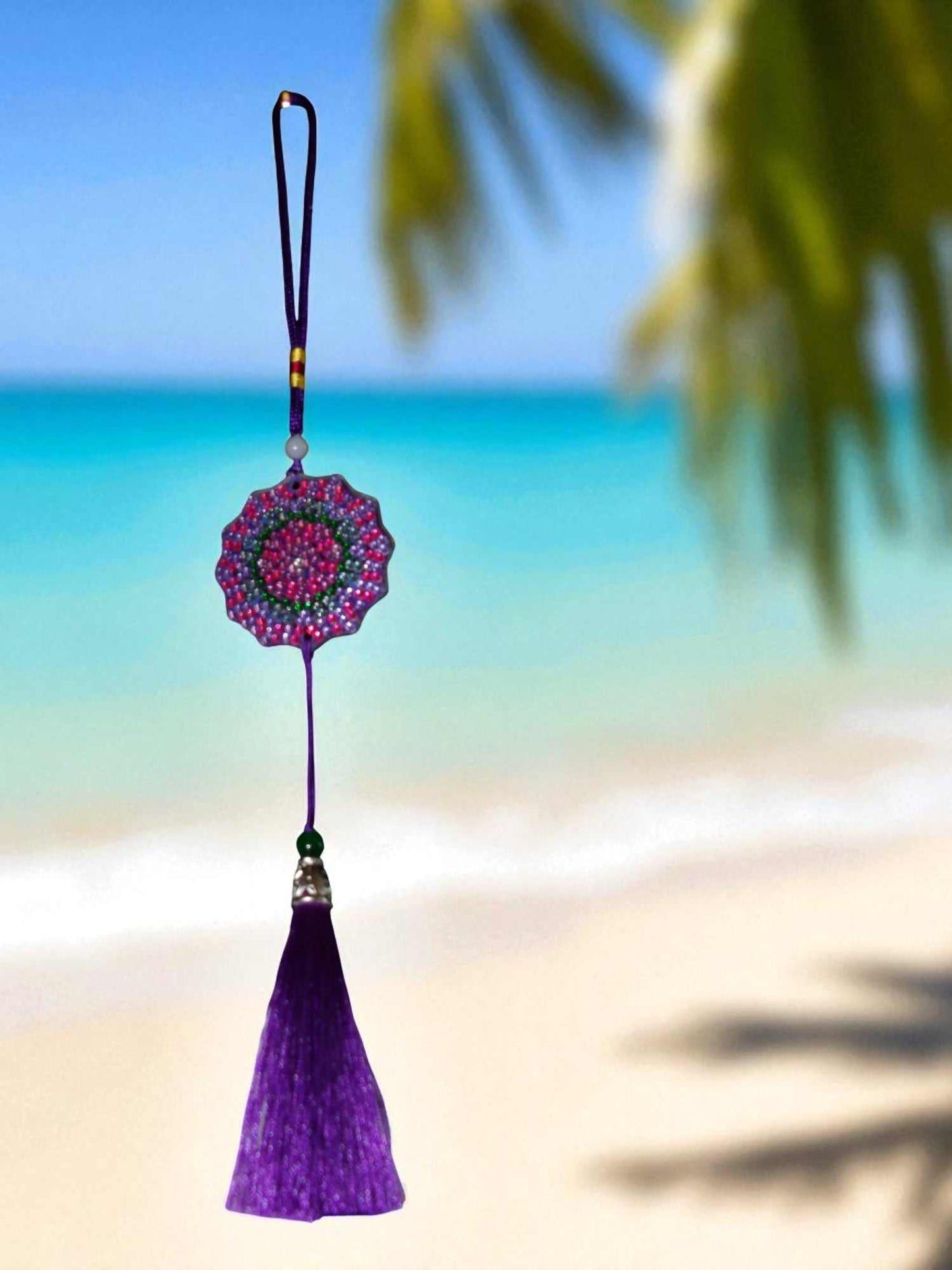 Deep blue colorful design car ornament hanging with purple tassel against beach background