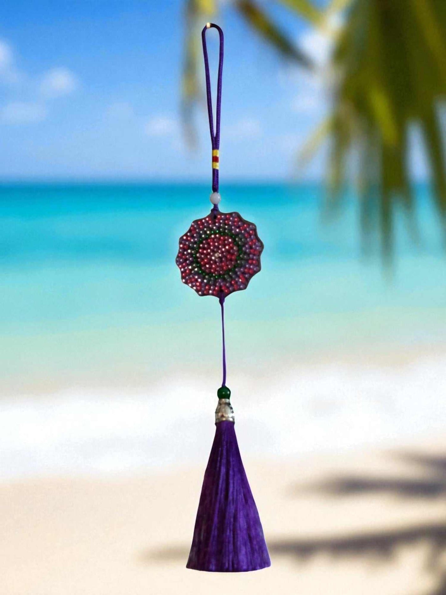 Deep blue colorful design car ornament with tassel hanging against beach background
