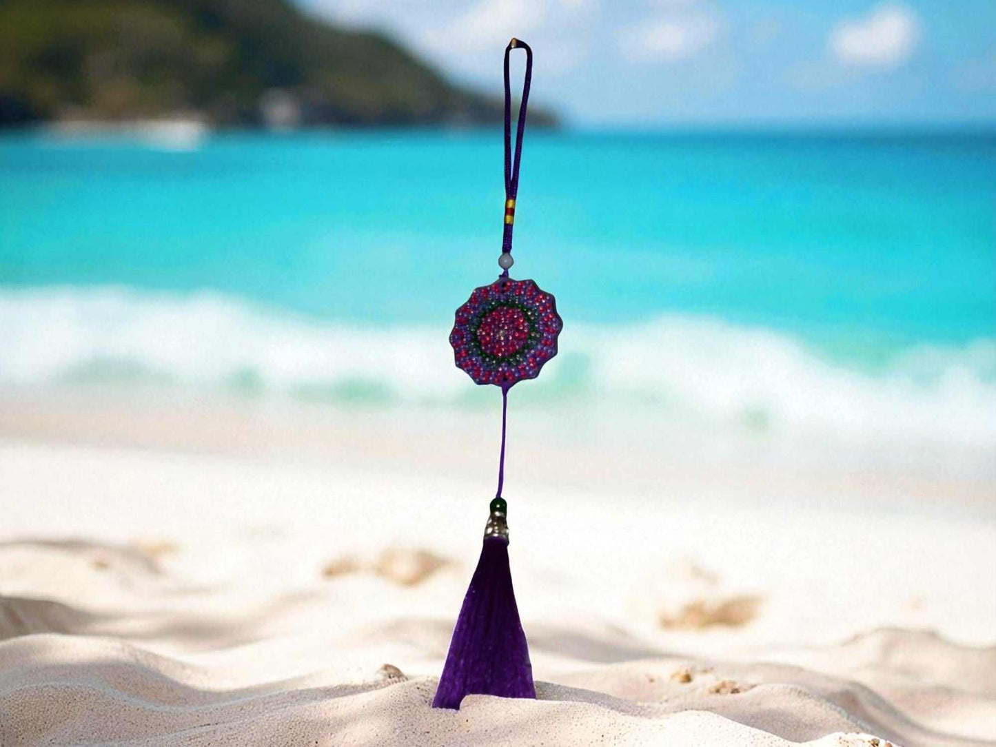 Deep blue colorful design car ornament with tassel hanging on beach background