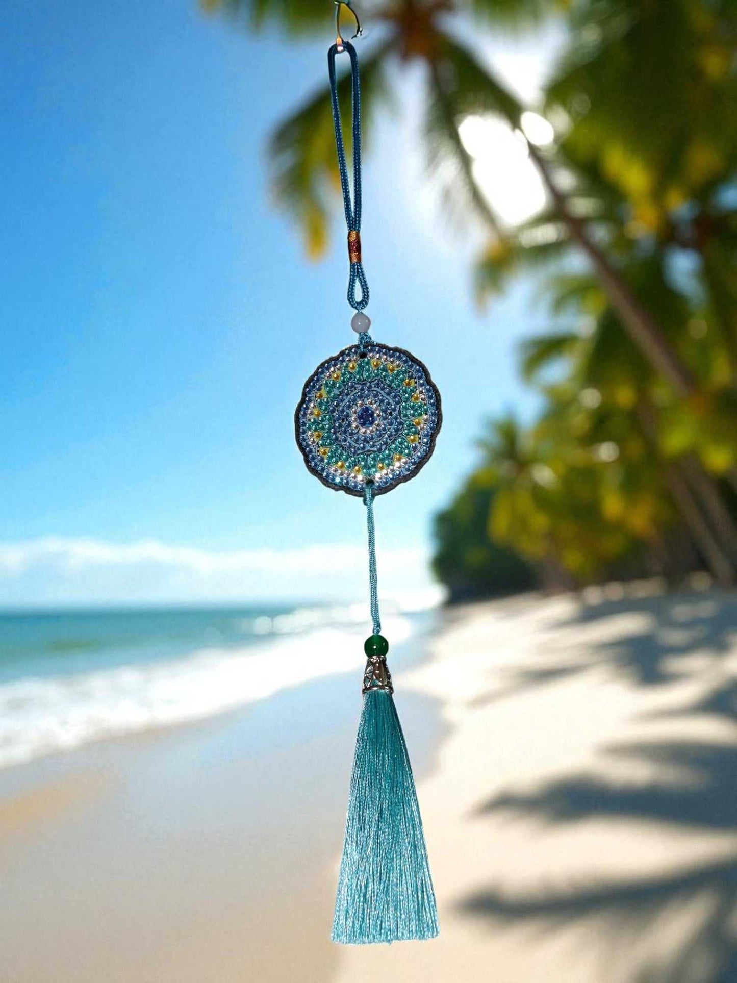 Sky blue colorful car ornament hanging with tassel on beach background