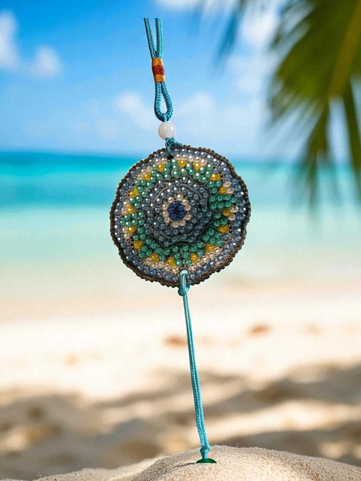 Sky blue colorful beaded car ornament hanging with beach and ocean background