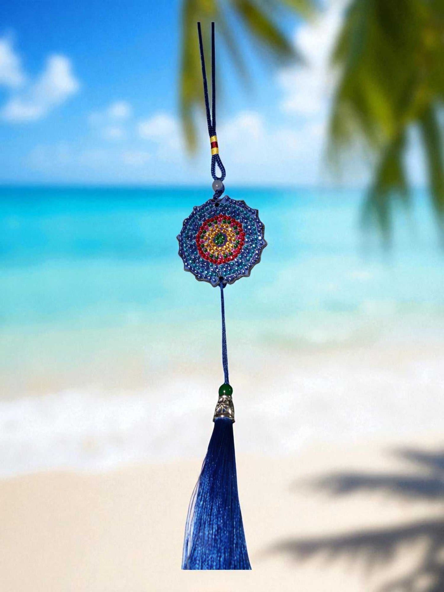 Dark blue colorful design car ornament hanging with tassel against beach background