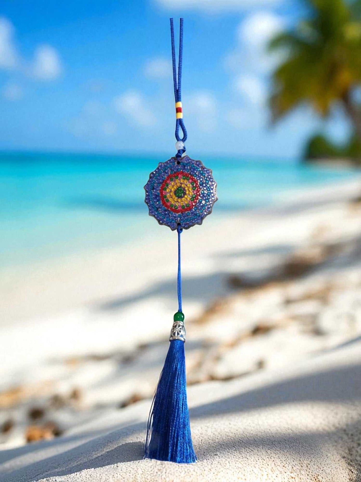 Dark blue colorful design car ornament hanging with tassel on beach background