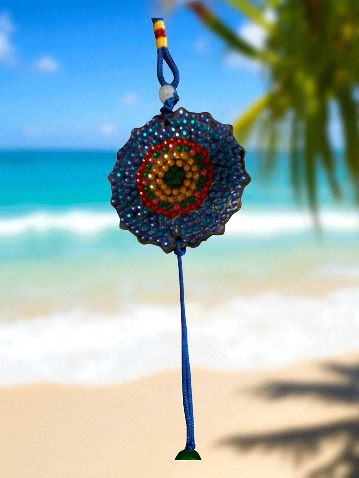 Dark blue colorful design car ornament hanging with vibrant circular pattern against beach background