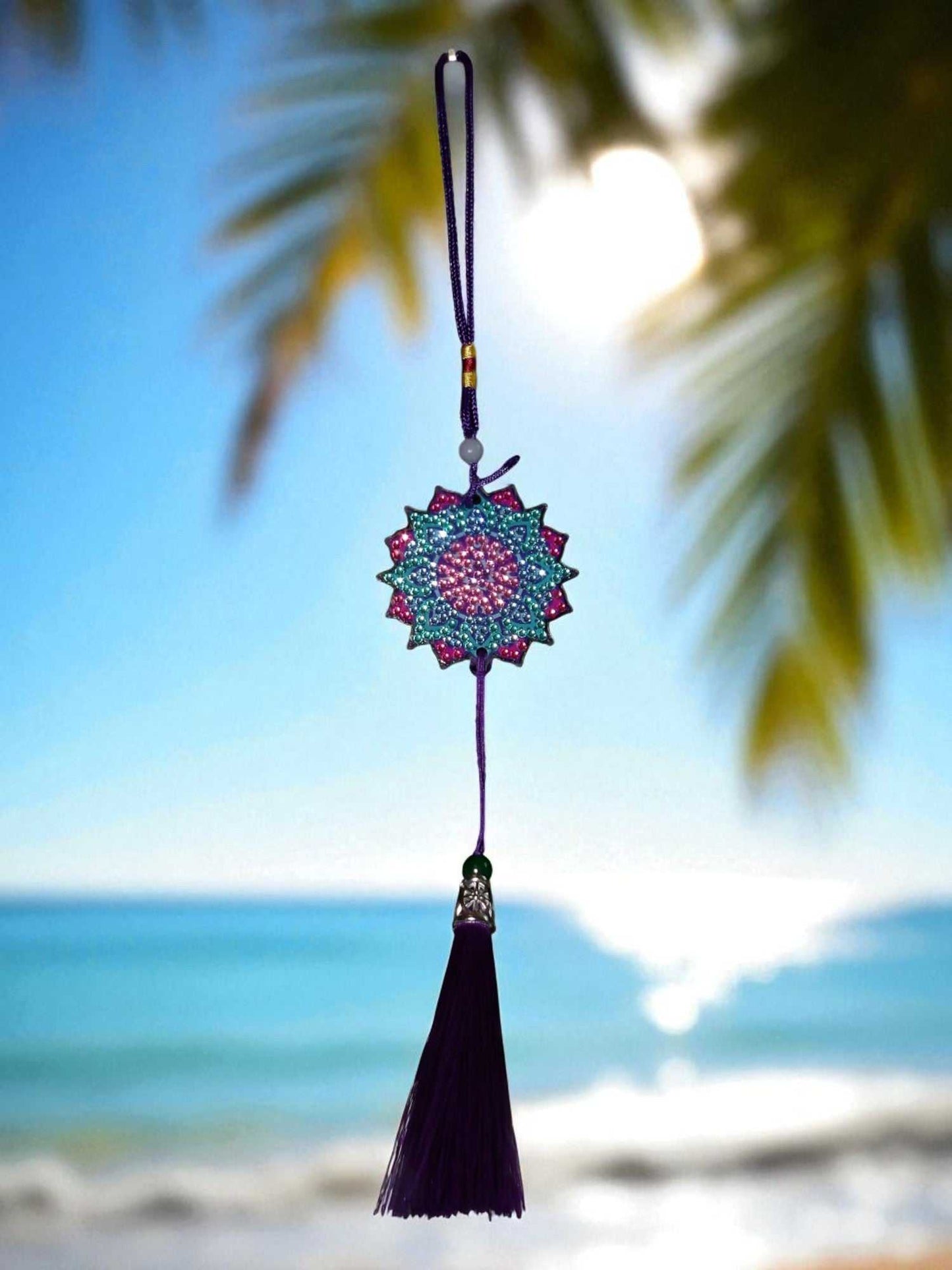 Navy blue colorful design car ornament with tassel hanging in front of beach background