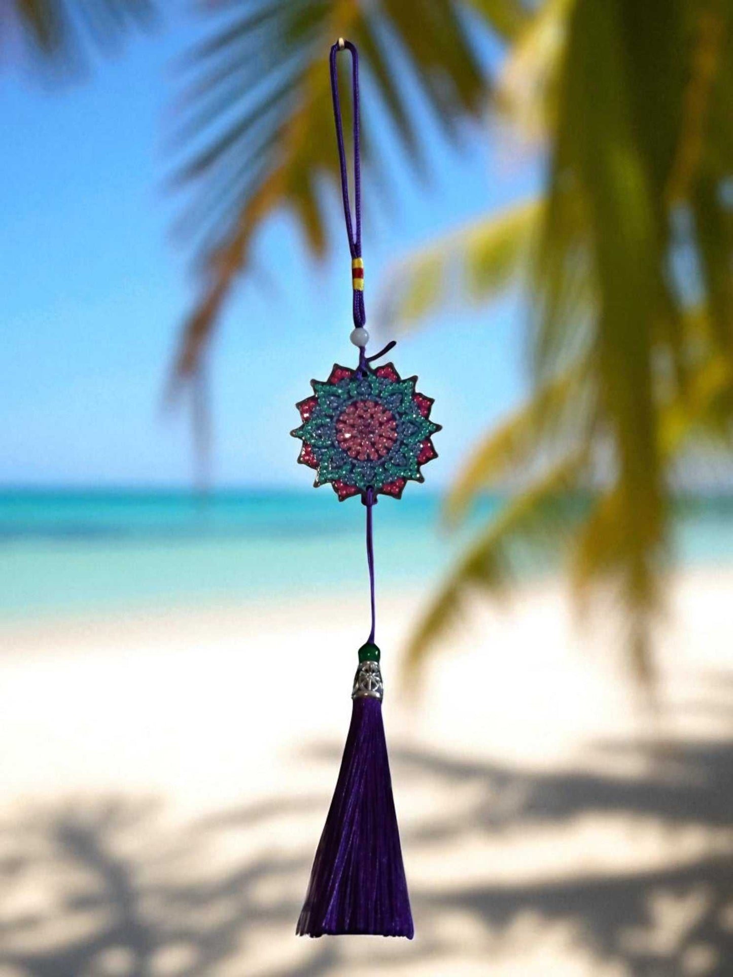 Navy blue colorful design car ornament with tassel hanging by a beach background