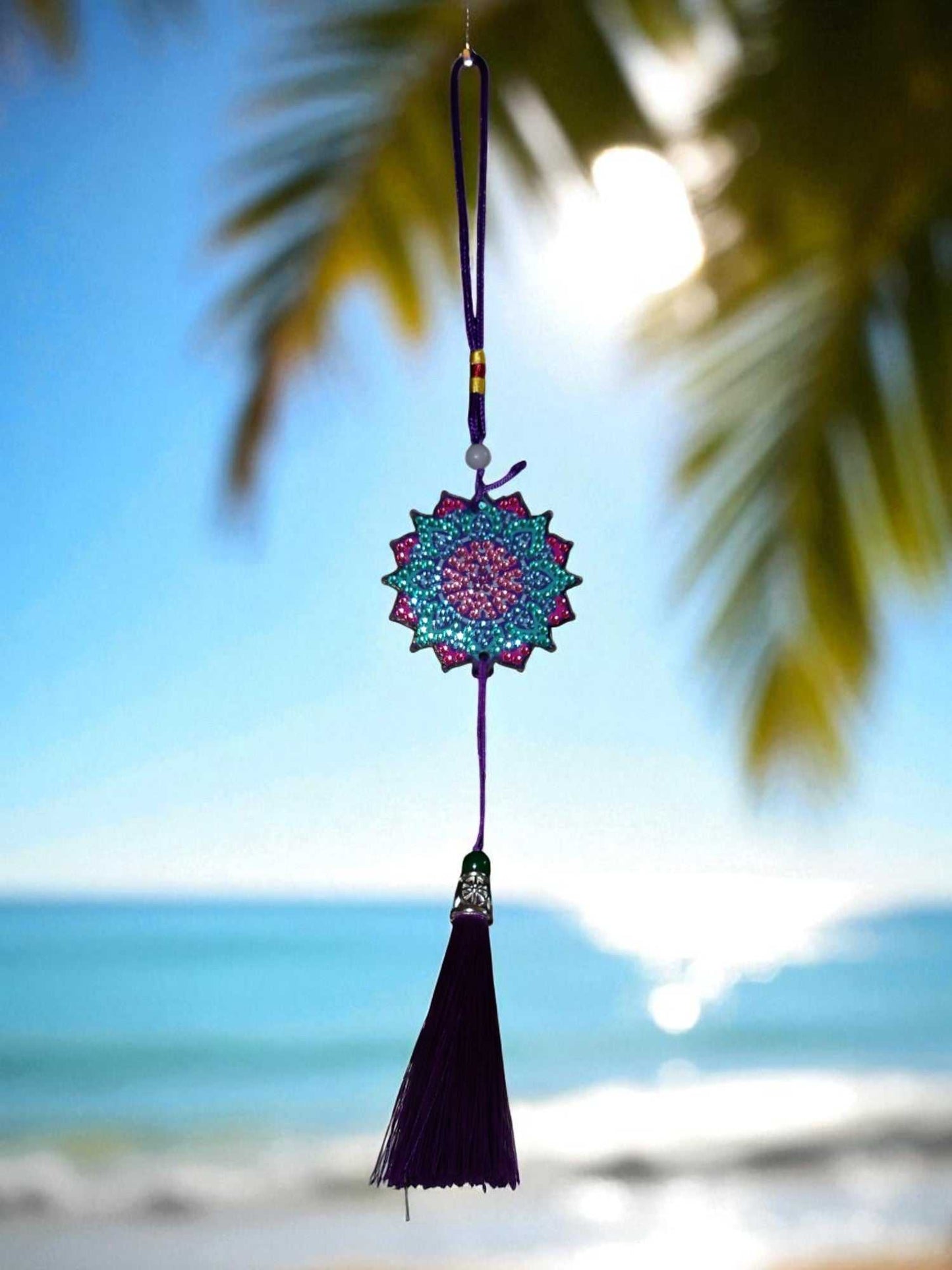 Navy blue colorful design car ornament hanging with tassel against beach background